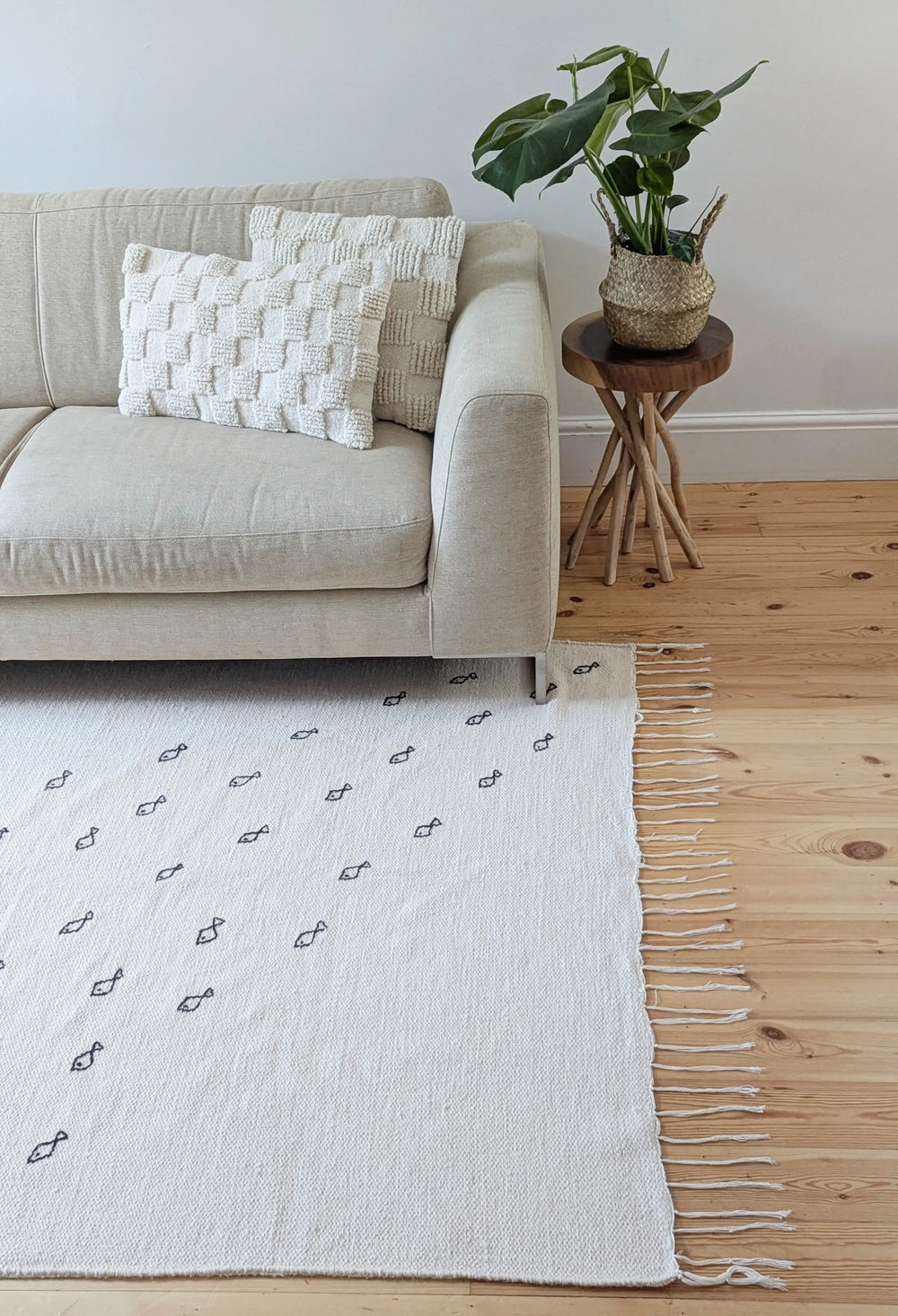 Fish symbols embroidered on natural wool berber rug in living room next to sofa