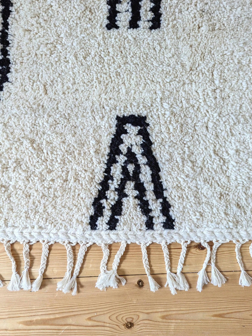 Black and cream natural wool berber rug with abstract design and plaited tassels